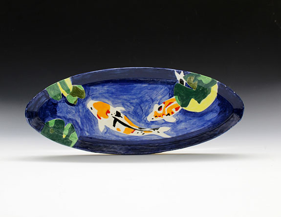 Long, blue ceramic plate with painted koi fish and lily pads.