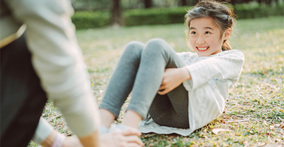 Child doing a sit up while someone holds their feet