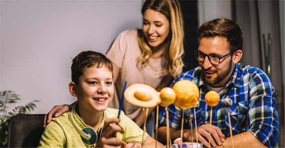 Child with parents looking at solar system project