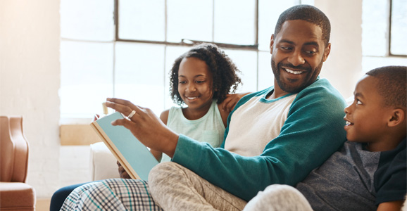 An adult reading a book to two children