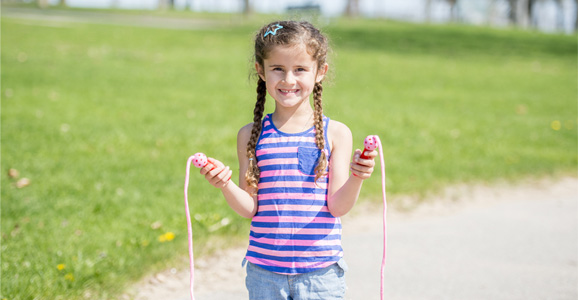 Child standing outside with jump rope