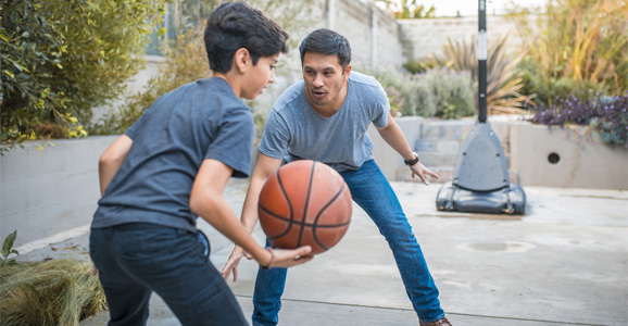 An adult playing basketball with a child